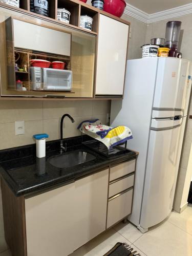 a kitchen with a sink and a refrigerator at Apto aconchegante nos Bancários 65m in João Pessoa