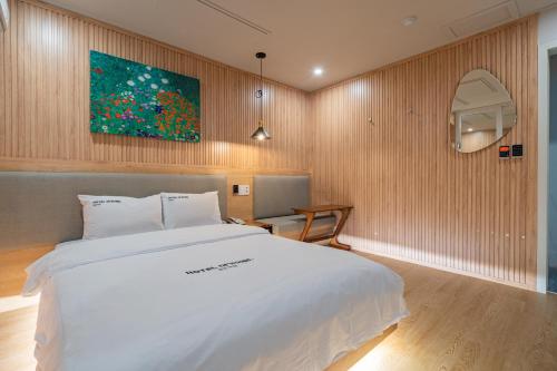 a bedroom with a white bed and a painting on the wall at Hotel Yoegieottae Gwangju Station in Gwangju