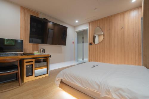 a bedroom with a bed and a desk and a television at Hotel Yoegieottae Gwangju Station in Gwangju
