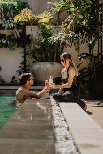 a man and a woman sitting next to a swimming pool at La Bastide de Caro in Siem Reap