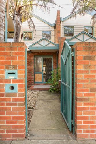 a brick house with a green gate in front of it at Glorious 3-BRM Family House at Aspendale Beach in Aspendale