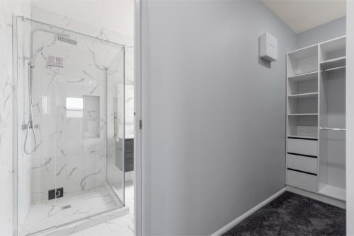 a shower with a glass door in a bathroom at Beach Revival - Clarks Beach Holiday Home in Clarks Beach