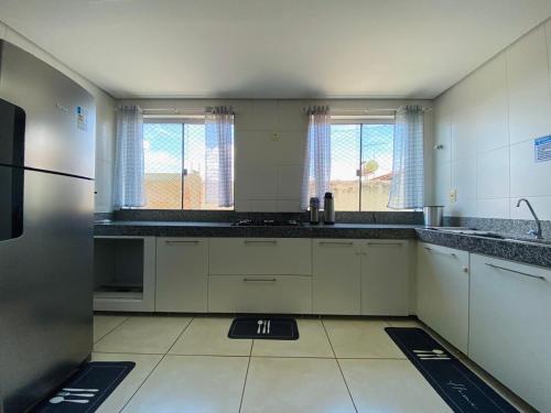 a kitchen with white cabinets and black counter tops at Apartamento Bela vista in Brumadinho