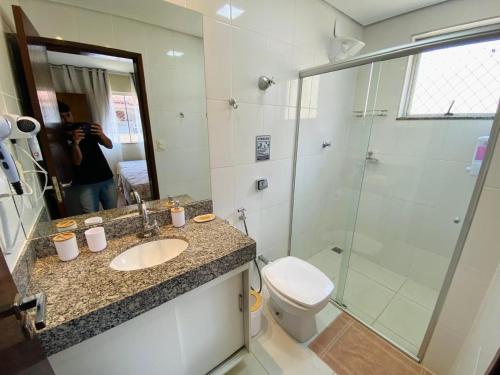 a woman taking a picture of a bathroom with a shower at Apartamento Bela vista in Brumadinho