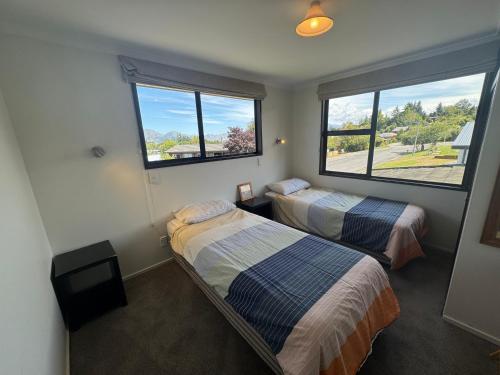 twee bedden in een kamer met twee ramen bij 66 Conical Hill Road in Hanmer Springs