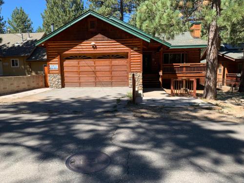 a house with a wooden garage with a tree at TimberWood Cabin- 3 Bdr - 2 Bth - Big Game room - Prime Location in Big Bear Lake in Big Bear Lake