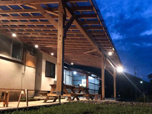a building with a picnic table under awning at night at 畑のおやど in Asago