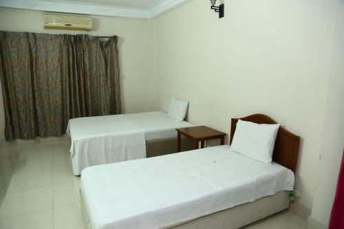 a room with two beds and a window at Maya Eco Guest House in Dhaka