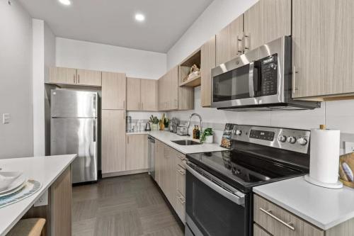 a kitchen with stainless steel appliances and wooden cabinets at Pinnacle Heights 2Bdrm 3rd flr Near Walmart Amp Pool Fitness Center Yoga Studio Dog Spa in Rogers