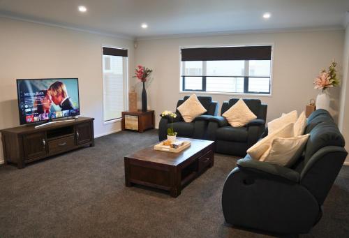 a living room with couches and a flat screen tv at Elite Escape Hawera in Hawera
