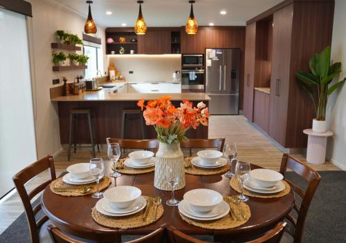 a dining room table with a vase of flowers on it at Elite Escape Hawera in Hawera