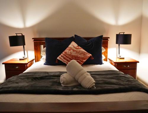 a bed with blue pillows and two lamps at Elite Escape Hawera in Hawera