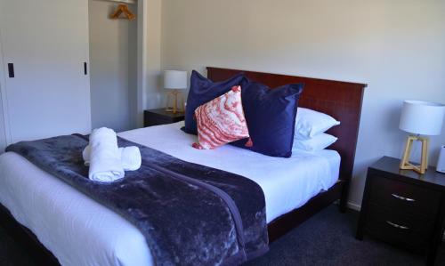 a bedroom with a large bed with blue pillows at Elite Escape Hawera in Hawera
