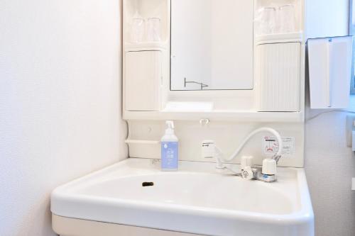 a white bathroom sink with a mirror and a bottle of soap at たび宿Yumiashi in Sendai