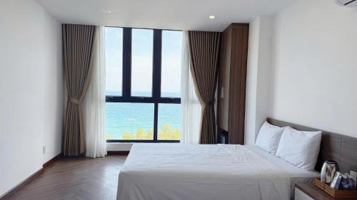 a bedroom with a white bed and a large window at AQua Hotel & Spa in Nha Trang
