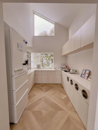 a kitchen with white cabinets and a window at 雪玉Snowball Hostel in Furano