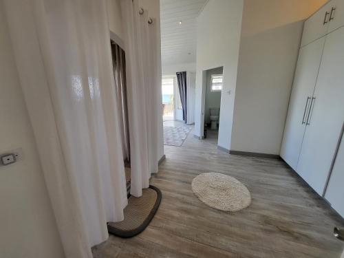 a hallway with white curtains and a rug on the floor at Unique Villa Retreat Style! Full Sea Views & Pool! villa in Christ Church