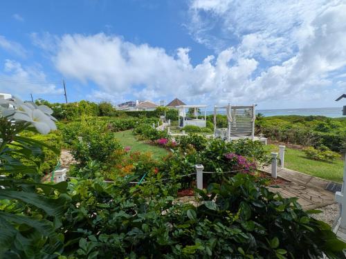 a garden with flowers and a chair and the ocean at Unique Villa Retreat Style! Full Sea Views & Pool! villa in Christ Church