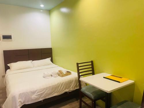 a bedroom with a bed and a table and a chair at Kayong's Inn in Dumaguete