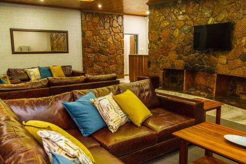 a living room with a leather couch and a television at Blyde Canyon, A Forever Resort in Matibidi