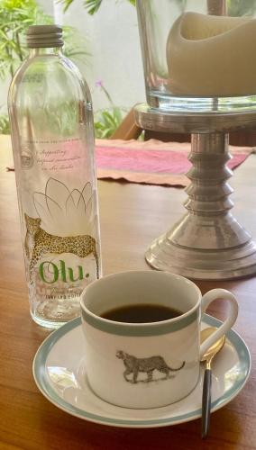 a cup of coffee on a plate next to a bottle at Star Light Tropical Villa in Bentota