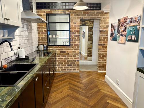 a kitchen with wooden floors and a brick wall at Cronulla Beach Escape - Walk To Beach - Parking in Cronulla