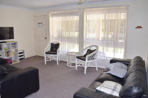 a living room with a couch and two chairs and a table at Chel Sea in Hat Head