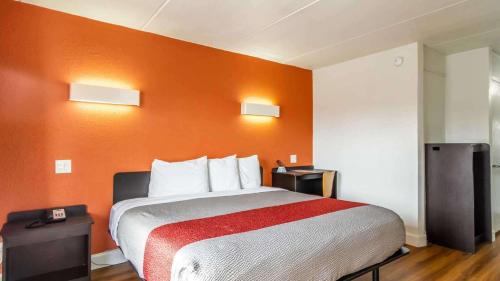 a hotel room with a bed with an orange wall at Motel 6-Brunswick, GA in Brunswick