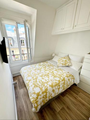 une chambre avec un lit avec une couverture jaune et blanche dans l'établissement Appartement cosy au cœur du Paris 17eme, à Paris