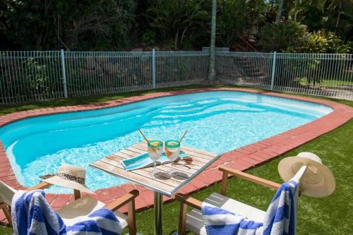 a swimming pool with two glasses and a table with chairs at Beach House on Begley- Airlie Beach Central in Airlie Beach
