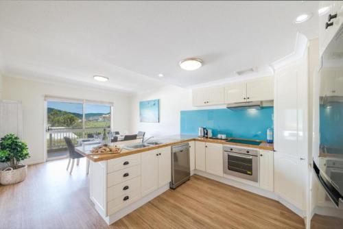 a kitchen with white cabinets and blue accents at Beach House on Begley- Airlie Beach Central in Airlie Beach