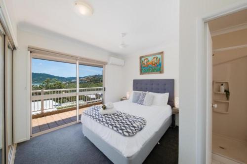 a bedroom with a bed and a balcony at Beach House on Begley- Airlie Beach Central in Airlie Beach