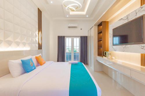 a bedroom with a large bed with a tv on the wall at Sans Hotel Sky Home Syariah Tegal in Tegal