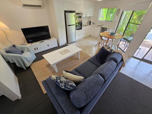 a living room with a blue couch and a table at Noosa River Retreat Holiday Apartments in Noosaville