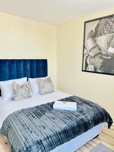 a bedroom with a large bed with a blue headboard at C&J Luxe Apartments in Windhoek