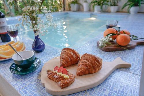 a table with croissants and fruit on a cutting board at Villa Nautica By The Beach - Vesta Collections in Hoi An