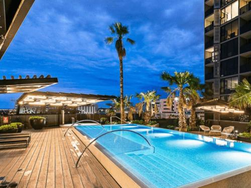 a swimming pool on a deck with a palm tree at North Melbourne Retreat in Melbourne