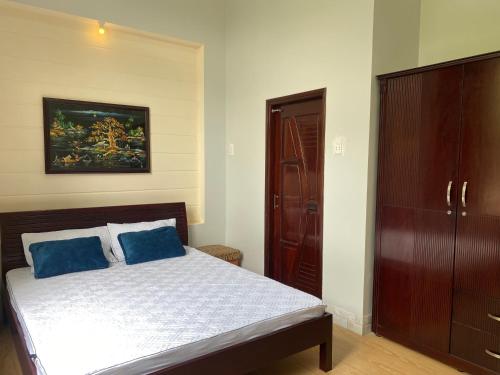 a bedroom with a bed with two blue pillows at Villa Nghỉ Dưỡng Nguyên Căn in Trung An