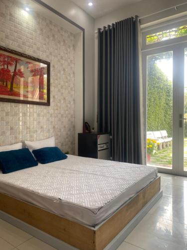 a bedroom with a large bed with blue pillows at Villa Nghỉ Dưỡng Nguyên Căn in Trung An