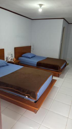 two beds sitting in a room with at Amora homestay in Sekongkang