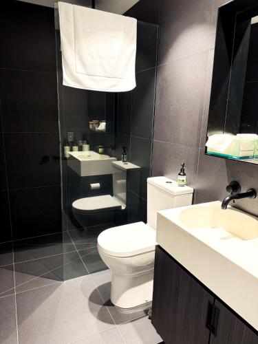 a bathroom with a toilet and two sinks and a mirror at North Melbourne Retreat in Melbourne
