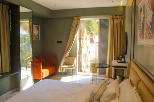 a bedroom with a bed and a chair and a window at Hotel Comfort Inn in Pune