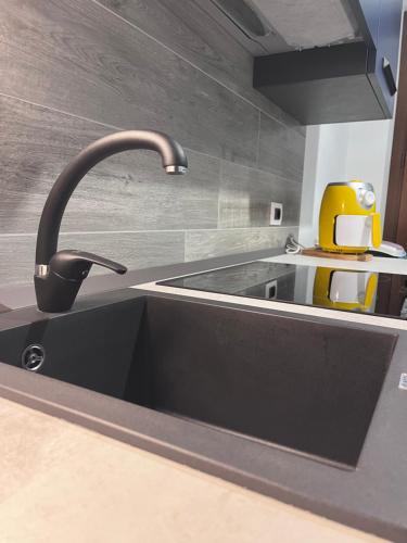 une cuisine avec un évier noir et un appareil jaune dans l'établissement Gassa d Amante Borghetto Santo Spirito, à Borghetto Santo Spirito