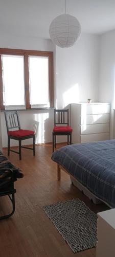a bedroom with two chairs and a bed and windows at Casa Monte Muggio in Casargo