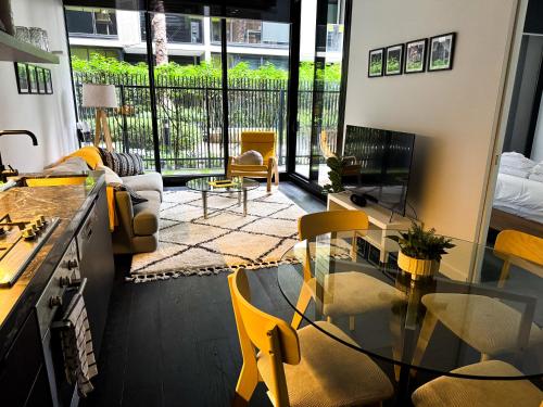 a living room with a glass table and yellow chairs at North Melbourne Retreat in Melbourne