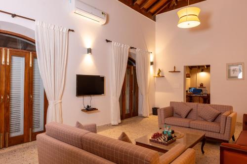 a living room with two couches and a tv at Rosastays Panjim North Goa in Goa
