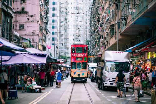 a red double decker bus driving down a busy city street at ibis Hong Kong North Point in Hong Kong