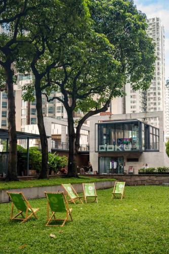 three lawn chairs sitting in the grass in front of a building at ibis Hong Kong North Point in Hong Kong