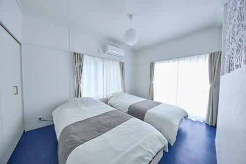 a bedroom with two beds and a large window at Chez Wataamé99 in Chosei
