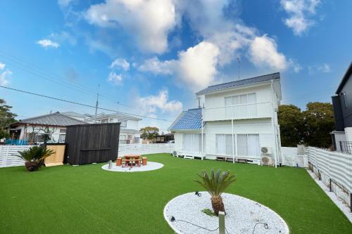 a backyard with a green yard with a white house at Chez Wataamé99 in Chosei
